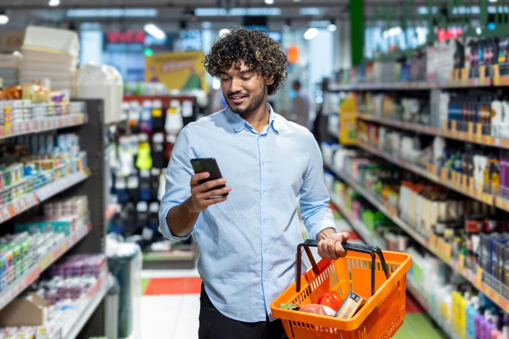 Hombre comprando en supermercado con su celular